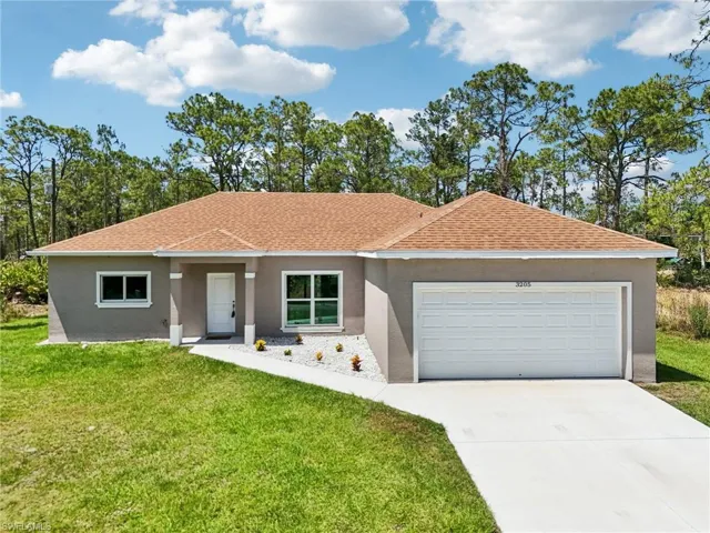 Single story home with stucco siding, a front yard, a garage, roof with shingles, and concrete driveway