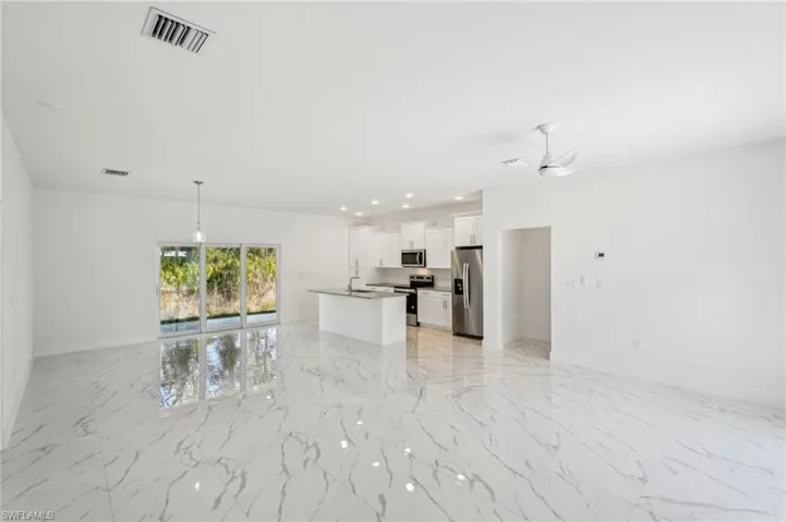 living room featuring light marble finish floors, ceiling fan, a sink, and baseboards