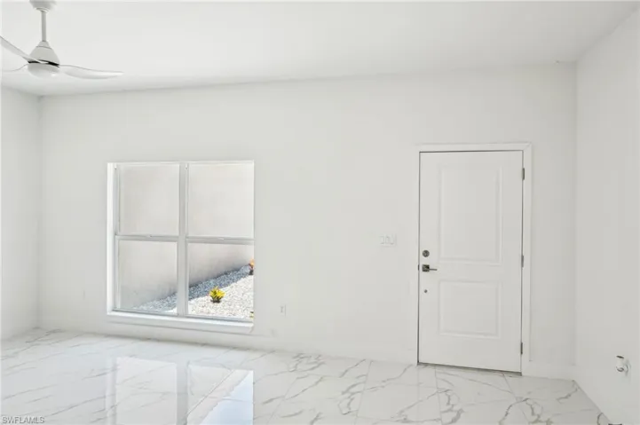 Spare room with light marble finish floors, ceiling fan, and baseboards