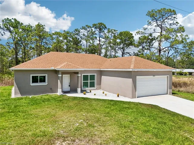 View of front of property with stucco siding, a garage, a front lawn, driveway, and a shingled roof