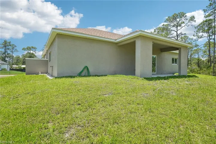 View of side of property featuring stucco siding and a yard