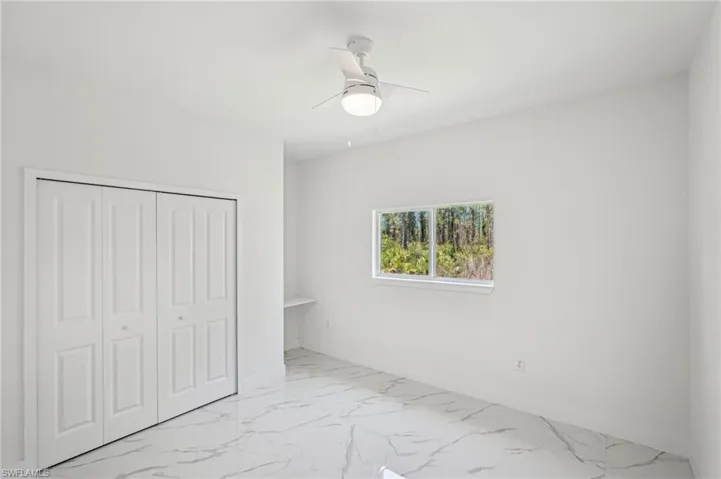 Unfurnished bedroom featuring marble finish flooring, a closet, ceiling fan, and baseboards
