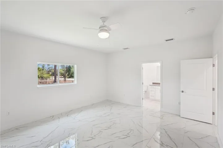 Unfurnished bedroom featuring light marble finish flooring, connected bathroom, and ceiling fan