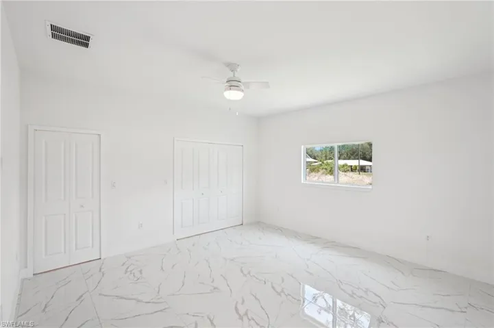Unfurnished bedroom featuring marble finish flooring and a ceiling fan