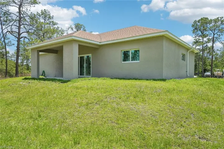 Rear view of property featuring stucco siding and a yard