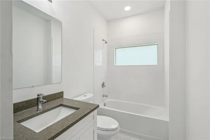 Bathroom with toilet, bathing tub / shower combination, and vanity