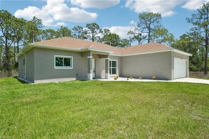 Modern-style house featuring stucco siding, a garage, a front yard, and driveway