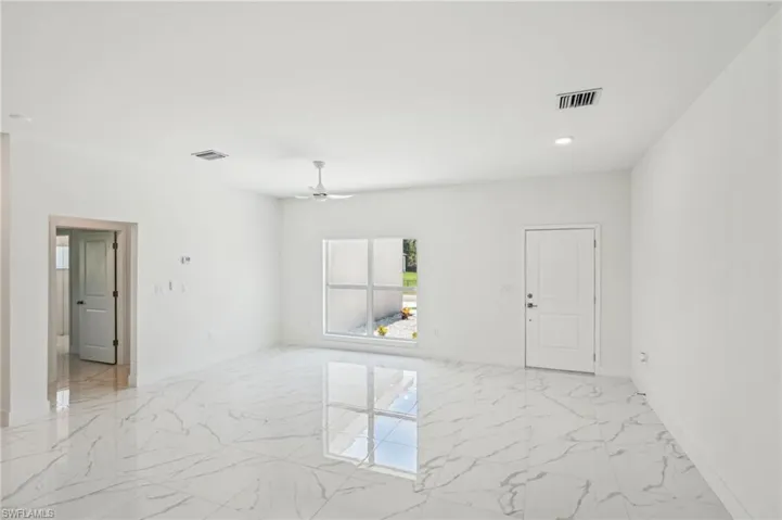 Empty room featuring light marble finish floors, a ceiling fan, and baseboards