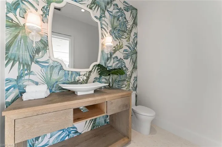 Custom vanity with an integrated vessel sink, framed mirror, and wall-mounted sconce lighting