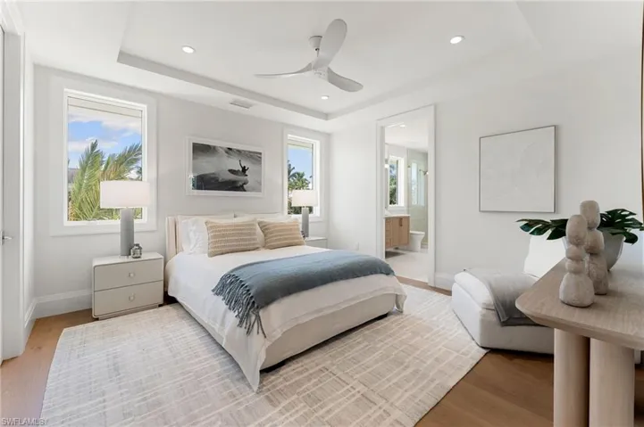 Recessed lighting, tray ceiling, ceiling fan, wood-finish flooring, and a doorway to an additional room