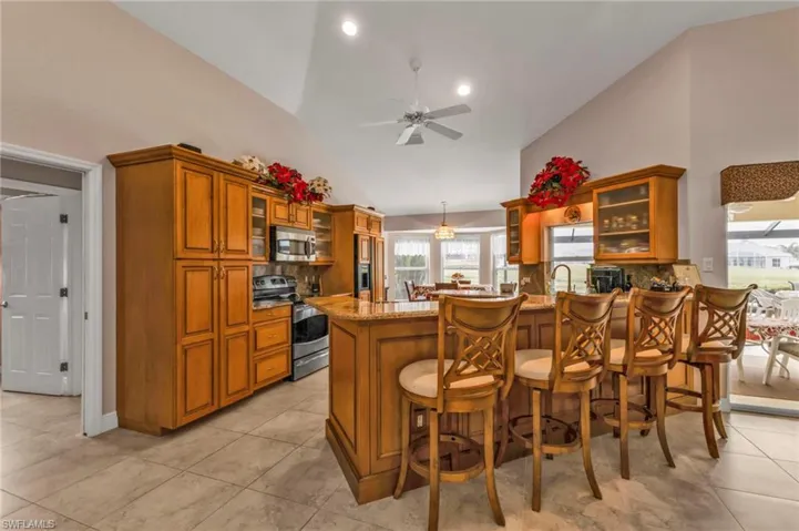 Kitchen with pendant lighting, appliances with stainless steel finishes, a kitchen breakfast bar, light stone countertops, and kitchen peninsula