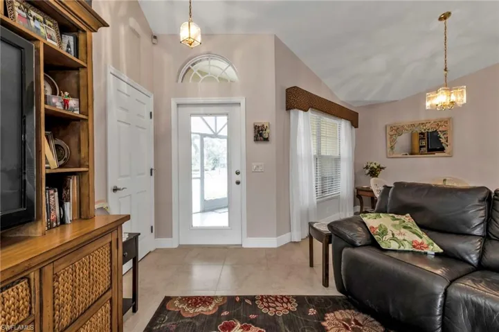 Tiled foyer featuring lofted ceiling, plenty of natural light, and a chandelier