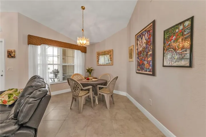 Tiled dining room featuring lofted ceiling and a chandelier