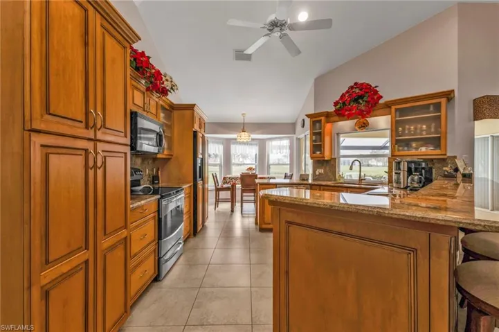 Kitchen with lofted ceiling, backsplash, stainless steel appliances, a kitchen bar, and kitchen peninsula