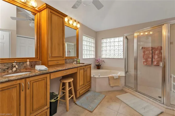 Bathroom featuring shower with separate bathtub, vaulted ceiling, vanity, ceiling fan, and tile patterned floors