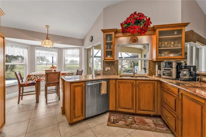 Kitchen featuring lofted ceiling, sink, hanging light fixtures, dishwasher, and kitchen peninsula