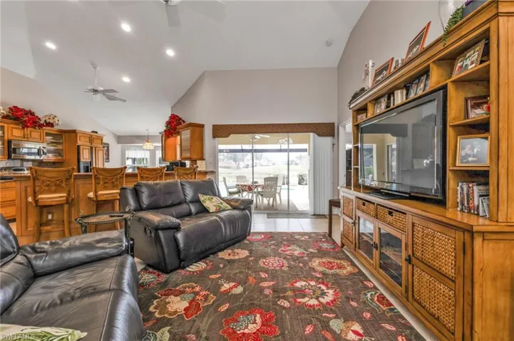 Living room featuring ceiling fan, light tile patterned flooring, and high vaulted ceiling