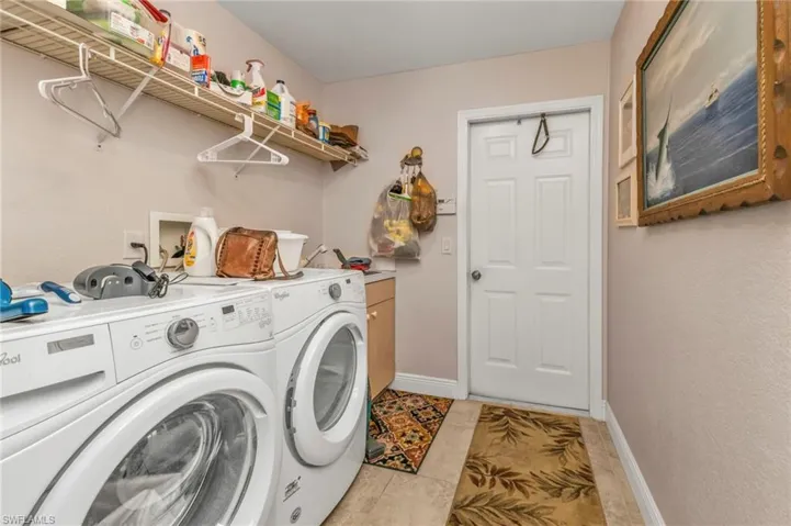 Washroom with cabinets, washer and dryer, and light tile patterned floors