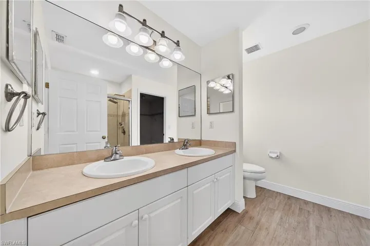 Bathroom featuring double vanity, a shower stall, and light wood-style floors
