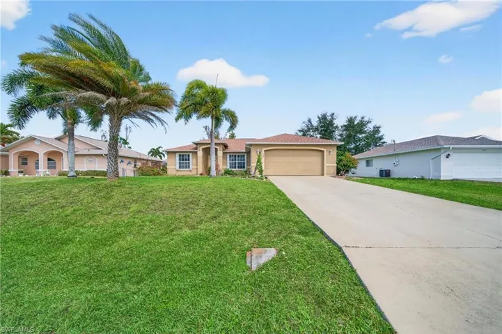 View of front of house with a garage, driveway, a front lawn, and stucco siding