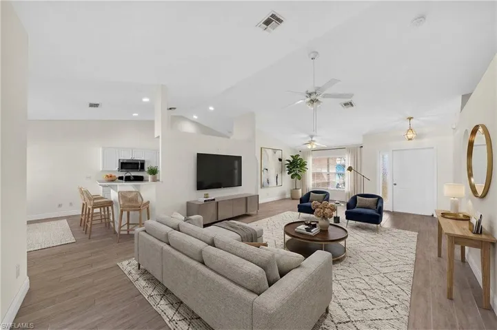 Living area with light wood finished floors, ceiling fan, and lofted ceiling