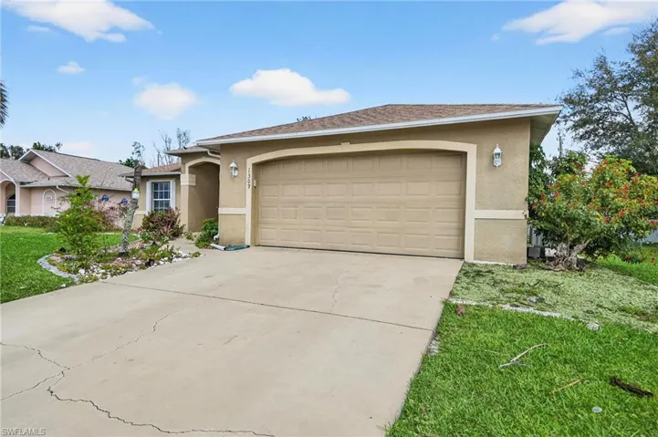 Ranch-style home featuring stucco siding, a garage, driveway, and a front yard