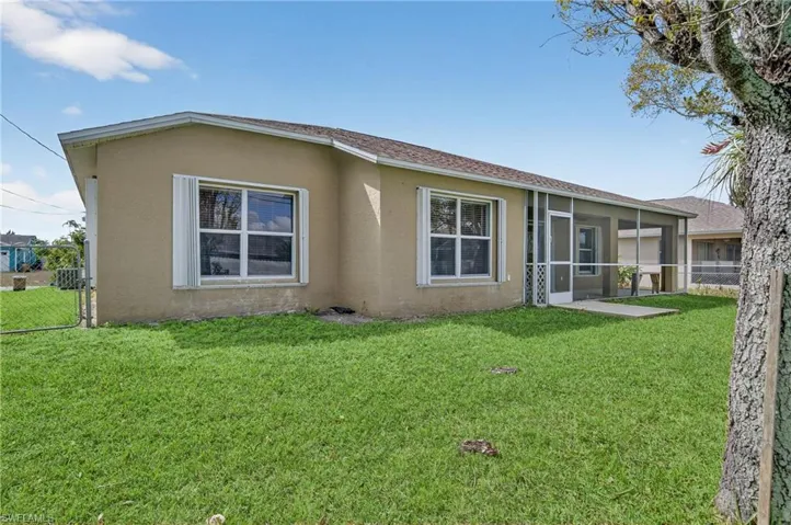 View of front of house with stucco siding, a sunroom, and a gate