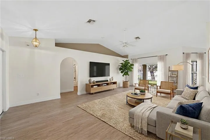 Living area featuring arched walkways, light wood-style floors, and ceiling fan