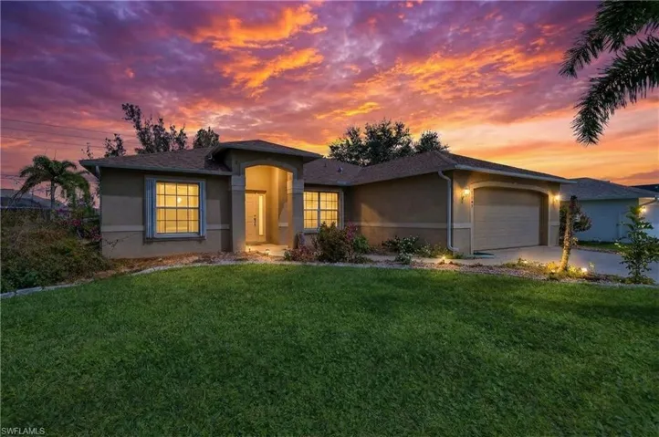 View of front of property with a garage, stucco siding, a lawn, and concrete driveway