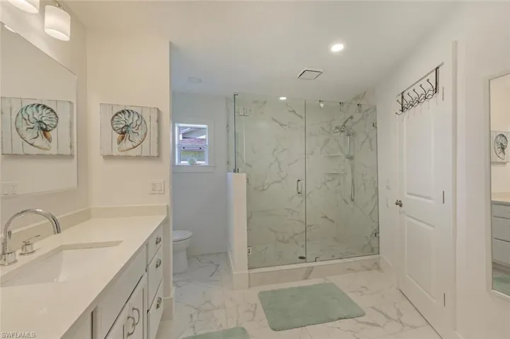 Bathroom with marble finish floors, a marble finish shower, vanity, toilet, and recessed lighting