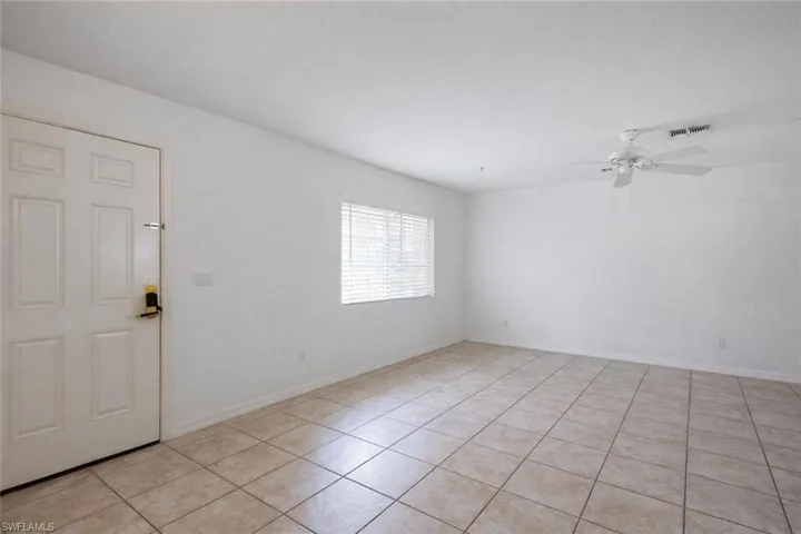 Empty room with a ceiling fan and light tile patterned floors