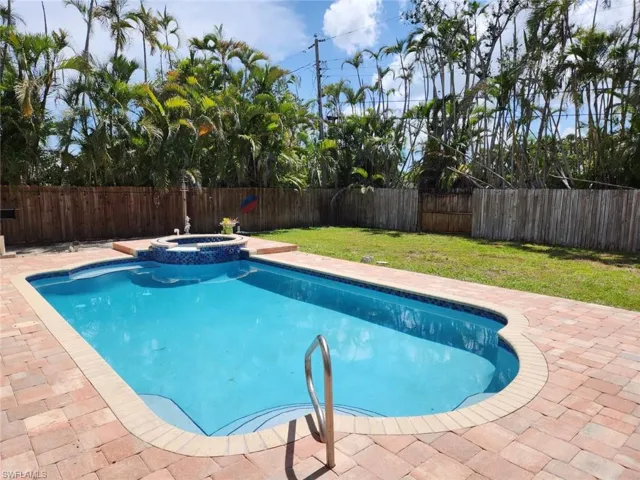 Swimming pool with integrated spa, paver deck, and lush tropical landscaping