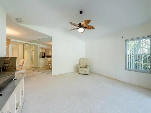 Living area with ceiling fan, vaulted ceiling, and light colored carpet