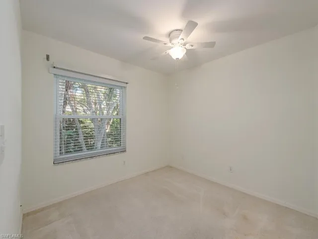 Empty room featuring light colored carpet and ceiling fan