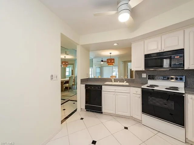 Kitchen with light tile patterned flooring, tasteful backsplash, white cabinets, ceiling fan, and black appliances
