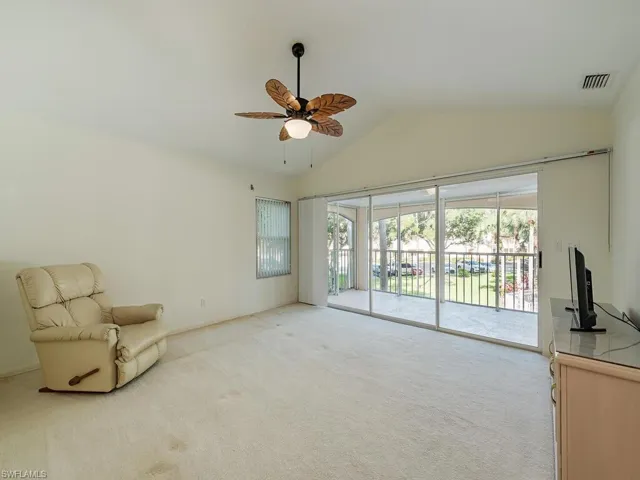 Sitting room featuring light carpet, ceiling fan, and vaulted ceiling