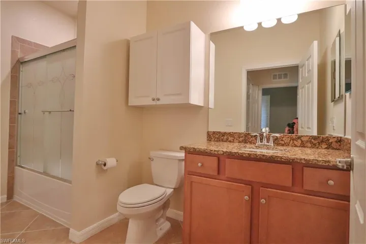 Full bathroom with toilet, vanity, tile patterned flooring, and enclosed tub / shower combo