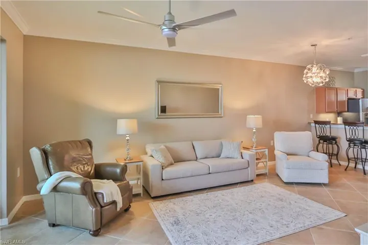 Tiled living room with ceiling fan and ornamental molding