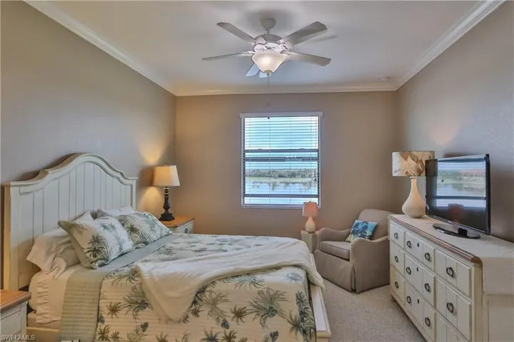 Carpeted bedroom with ceiling fan and crown molding