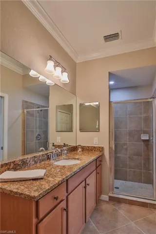 Bathroom with vanity, tile patterned flooring, crown molding, and walk in shower