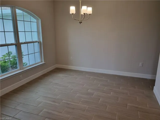 Empty room with wood-type flooring and an inviting chandelier