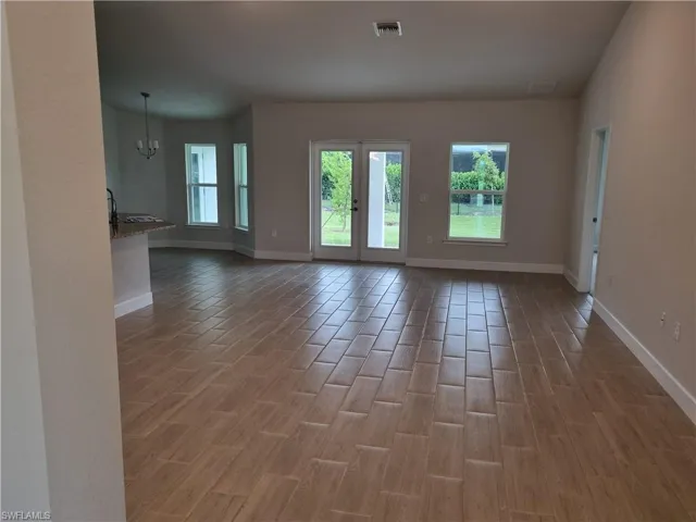 Empty room featuring hardwood / wood-style flooring and a notable chandelier