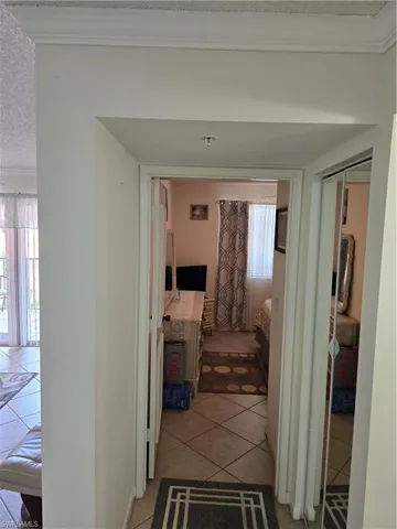 Corridor featuring crown molding and light tile patterned floors