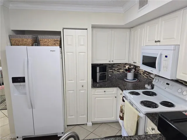 Kitchen featuring visible vents, ornamental molding, white appliances, white cabinets, and light tile patterned floors