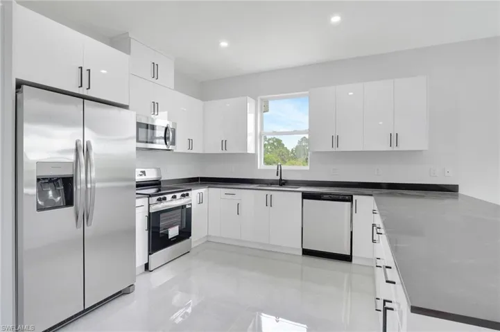Kitchen with stainless steel appliances, white cabinets, light tile patterned floors, recessed lighting, and a peninsula