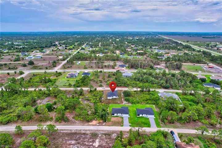 Aerial view of property's location with nearby suburban area and a tree filled landscape