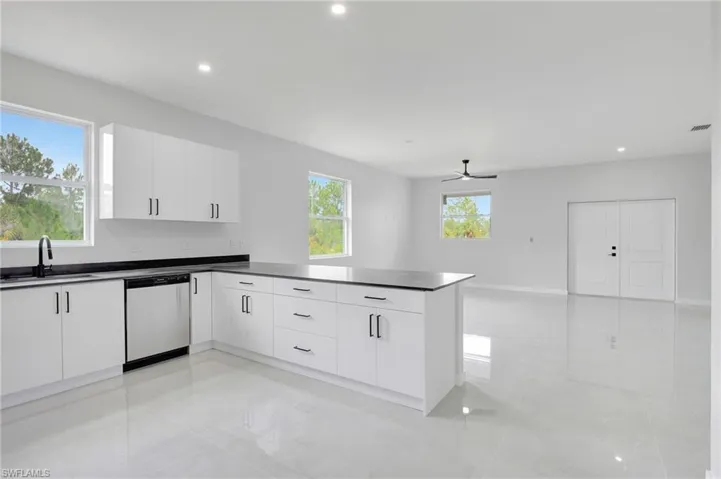 Kitchen featuring white cabinetry, a peninsula, recessed lighting, dark countertops, and stainless steel dishwasher