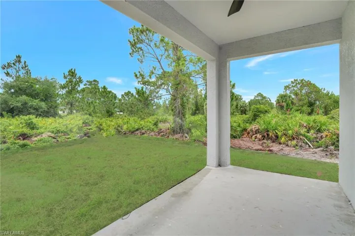 View of green lawn featuring a patio, view of scattered trees, and ceiling fan