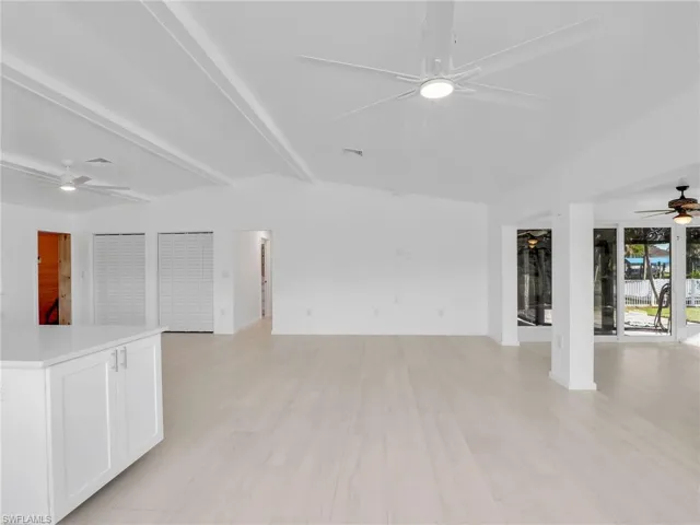 Unfurnished living room featuring beam ceiling and light hardwood / wood-style flooring