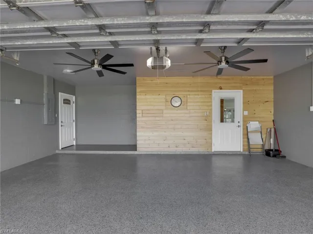 Garage featuring electric panel, wooden walls, and a garage door opener